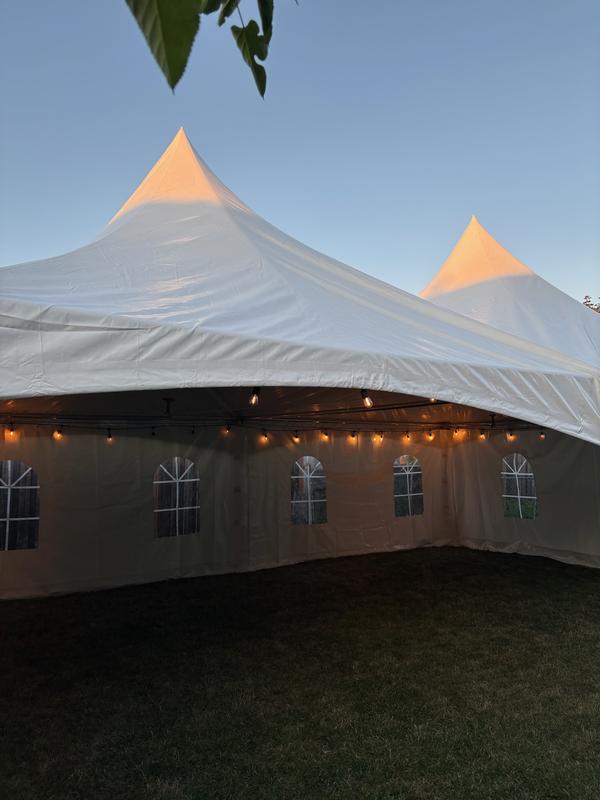 Evening view into a Skytop tent strung with bistro lights