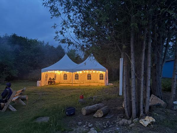 Skytop tent glowing among trees at night
