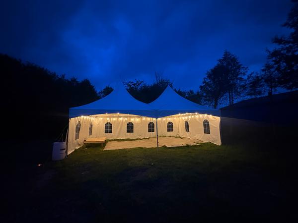 Long Skytop tent lit up at night on a lawn