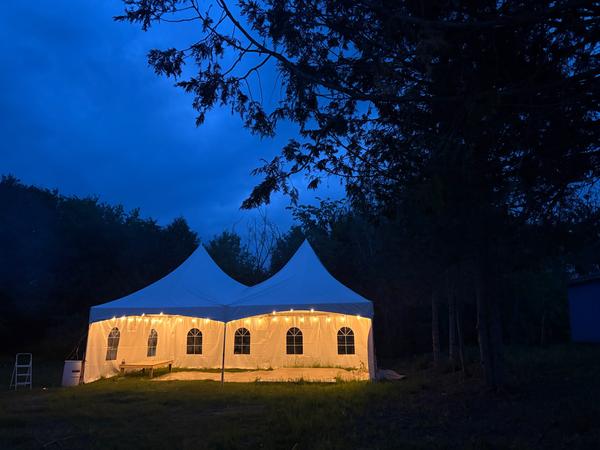 Single-peak tent glowing against the night sky