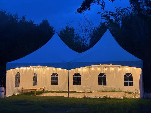 Twin-peak Skytop tent glowing with string lights at dusk