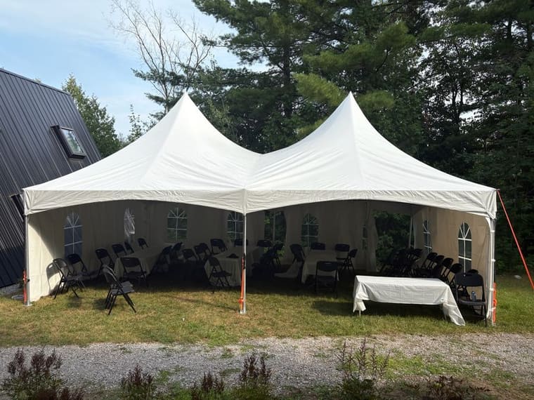 White peak tent set up beside a house for a backyard party